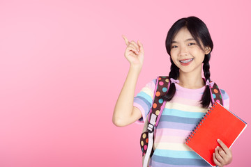 Happy Asian student holding red book and pointing with pink background and copyspace.