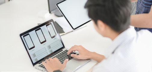 Close-up view of UI graphic designer planing on his smartphone template application with laptop