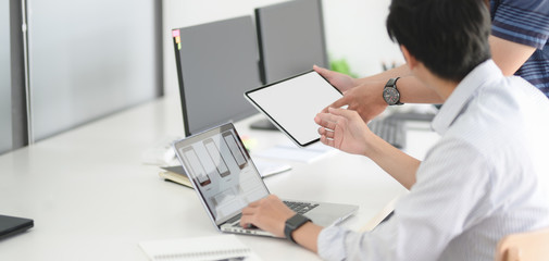 Cropped shot of young passionate UX web development team disscussing smartphone template with laptop