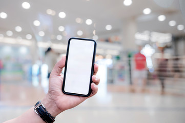 shot of man hand holding and showing blank screen smartphone while standing at shopping mall.