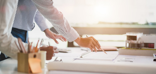 Close-up view of young professional architect and engineer working together on construction plans in modern office - obrazy, fototapety, plakaty