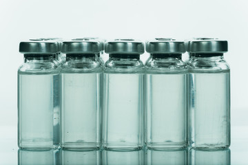 Glass medical ampoule vial for injection. Medicine is liquid sodium chloride with of aqueous solution in ampulla. Close up. Bottles ampule multicolor on background color and water. Human plasma.