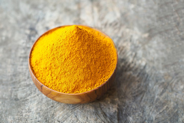 Turmeric powder in wooden bowl on old wooden table background. herbal