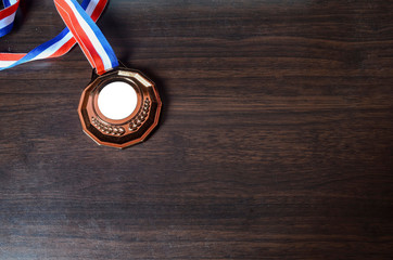 Bronze medal on wooden desk background. Selective focus.