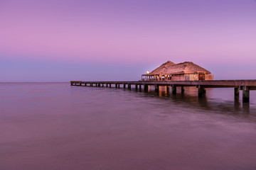 A view of the bungalow overwater beautifully lit up at dusk in Belize.