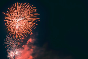 Beautiful festive red fireworks with smoke in the dark sky during a celebration with copy space....
