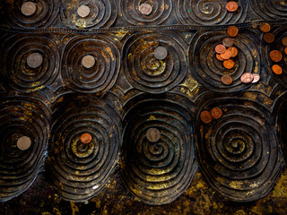 Many coins placed on replica of buddha footprint in the temple.