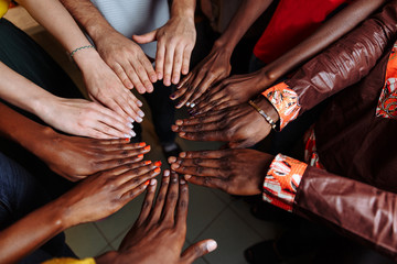 Hands of happy group of multinational African, latin american and european people which stay together in circle