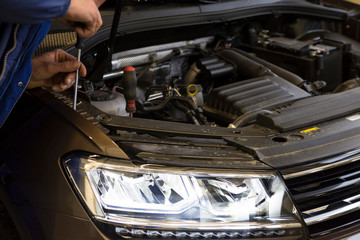 A mechanic adjusts the headlights on a car. Diode headlight of a modern car.