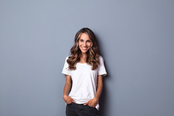 Indoor portrait of beautiful woman wearing white casual T-shirt, looking happily in camera.