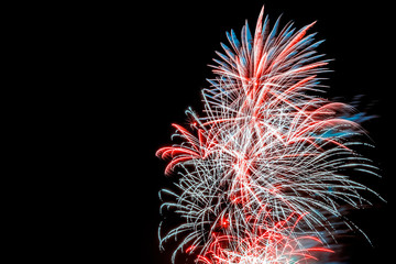 Several festive explosions of red and blue fireworks in the dark sky during a celebration with copy...