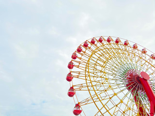 Big red Ferris wheel against white and blue sky