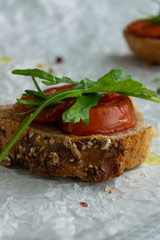 Delicious homemade bruschetta with whole grain bread, grilled tomatoes and fresh arugula. Vegetarian healthy snack, vegan food