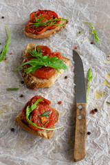 Delicious homemade bruschetta with whole grain bread, grilled tomatoes and fresh arugula. Vegetarian healthy snack, vegan food