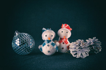 Couple of snowman, pine cones and garland, on blue background