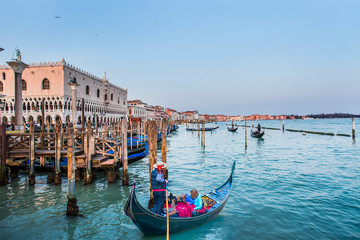 Fototapeta premium Venetian gondolier punting gondola through green canal waters of Venice Italy