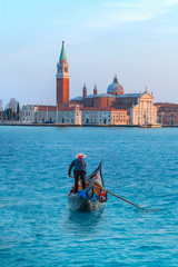 Venetian gondolier punting gondola through green canal waters of Venice Italy © muratart
