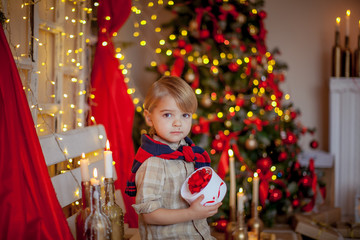 Boy 4-6 years old in a red festive room and a beautiful hairstyle on new year's eve.
