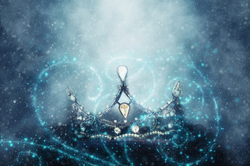 mysterious and magical photo of of beautiful queen/king crown over gothic snowy black background. Medieval period concept. Glitter sparkle lights