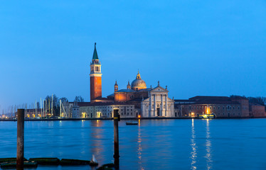 Fototapeta na wymiar View of San Giorgio Island in Venice with wooden buoys in Giudecca Canal at twilight blue hour - Venetian gondolier 