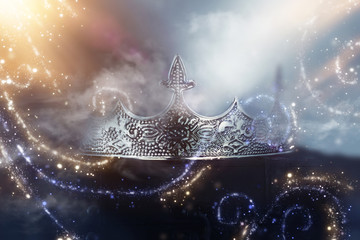 low key image of beautiful queen/king crown over wooden table. vintage filtered. fantasy medieval period. Glitter sparkle lights