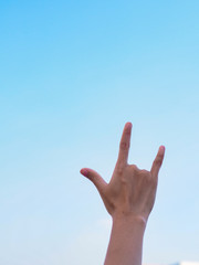 Human hand show love  sign on blue sky as a background.