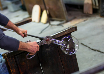 Glass blower at work shaping molten glass, Murano, Venice, Italy