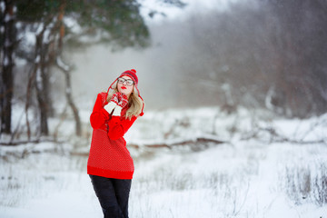 A woman in a red sweater in winter enjoys life in a snowy glade.