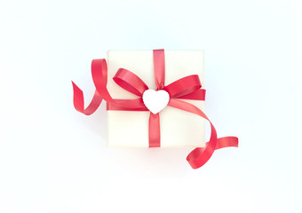 White gift box with red ribbon and white heart on white background. Valentine's Day concept. Valentine greeting card. Flat lay style. 