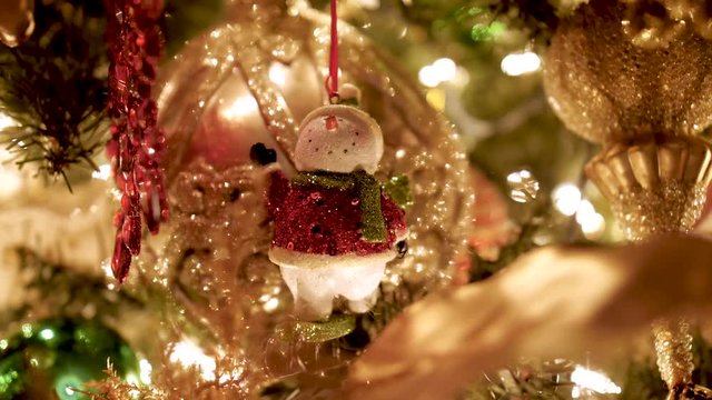 A happy sparkling snowman is hanging on a Christmas tree