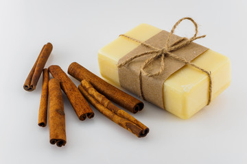 Yellow handmade soap and cinnamon sticks on white background