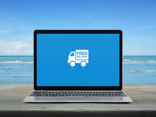Free delivery truck flat icon with modern laptop computer on wooden table over tropical sea and blue sky with white clouds, Business transportation online concept