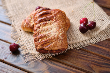Puffs with cherry jam on burlap on a wooden background. Rustic style