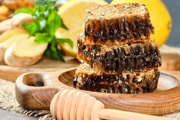 honey in honeycombs on a wooden plate and honey with nuts with lemon and ginger in rustic style on a wooden background.
