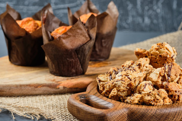 caramel waffles on a wooden plate and cupcakes on a gray background.