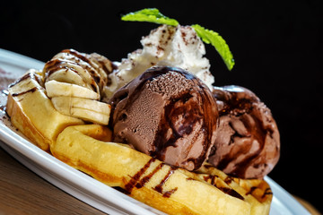 Waffle topped with chocolate ice cream , banana and wipe cream