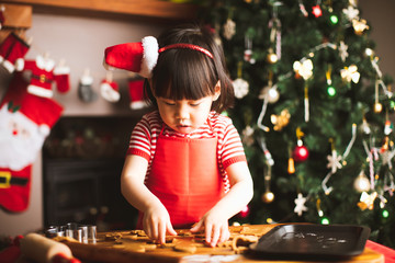 toddler girl making gingerbread man in front of Christmas tree
