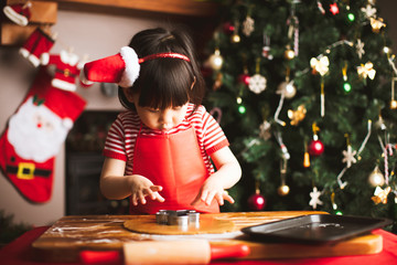 toddler girl making gingerbread man in front of Christmas tree