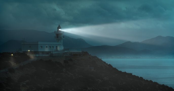 A mystical light mood at the lighthouse of Mazarron near the Spanish port city of Cartagena. After sunset, it gets dark, it's foggy and the rays of light go over the sea.