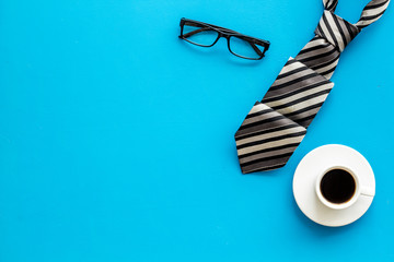 Father's birthday concept. Men's tie, coffee, glasses on blue background top-down copy space
