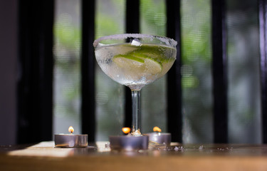 Delicious margarita cocktail with lime in a glass on dark background.