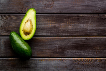 Avocado - whole and halfs - frame on dark wooden background top view copy space