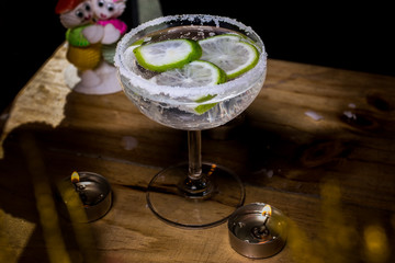 Delicious margarita cocktail with lime in a glass on dark background.