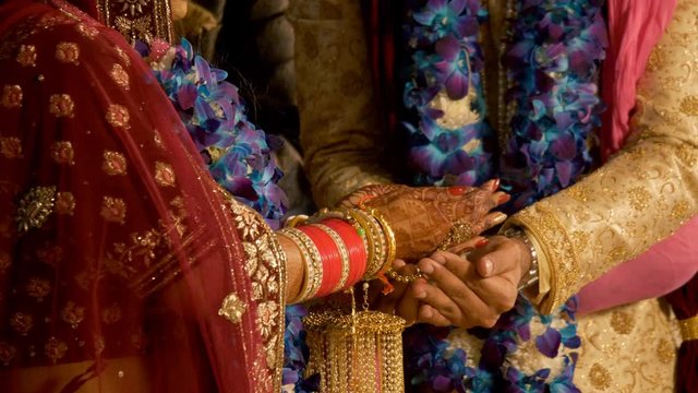 Indian wedding ritual - Bride and Groom holding each others hand. 4K stock footage of Indian wedding ceremony where the bride is giving puffed rice to grooms hand during their wedding ceremony  