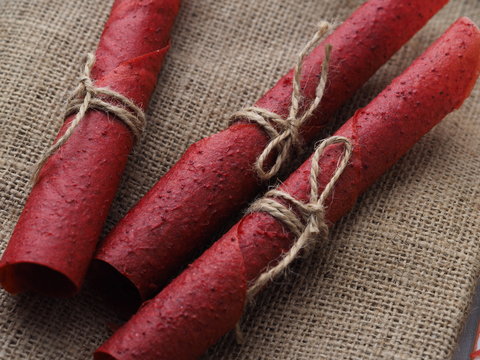 Red strawberry fruit leather rolls lie on the brown sacking