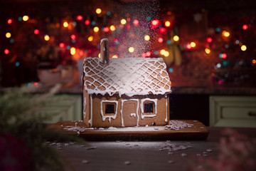 Gingerbread house sprinkled with icing sugar like snow. The spirit of Christmas. Garland on the...