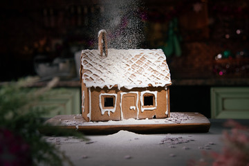 Gingerbread house sprinkled with icing sugar like snow. The spirit of Christmas. Garland on the...