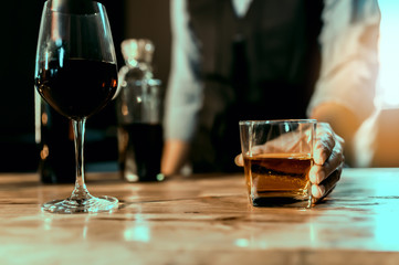 Hands of a bartender, with a glass of whiskey, soft focus.