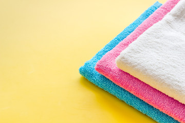 Clean towels - stack of laundred linen - on yellow background copy space