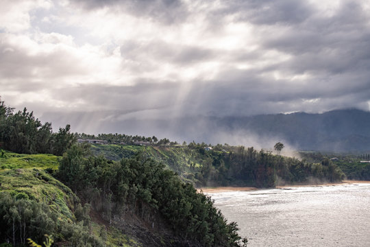 moody picture of the coast with sun rays coming through grey clouds on Hawaii